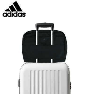 adidas Shoulder Bag positioned on top of a white suitcase, showcasing its sleek design.