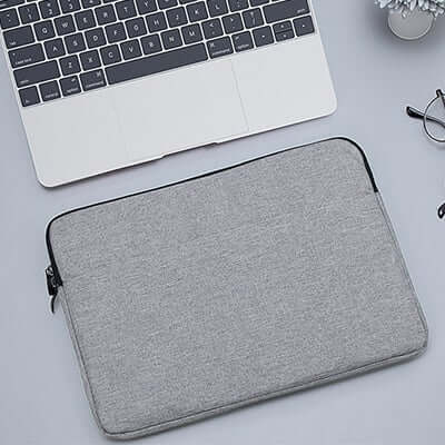 Light grey padded laptop sleeve with zip closure shown beside an example laptop
