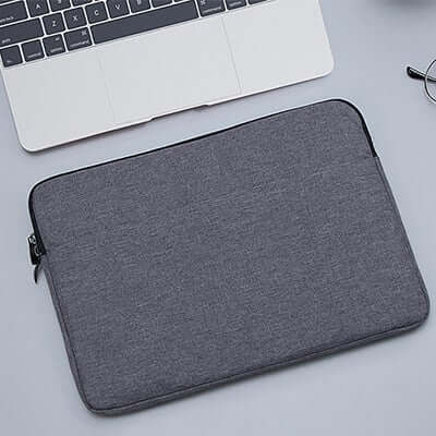 Dark grey padded laptop sleeve with zip closure shown beside an example laptop