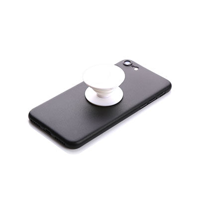 Pale round collapsible phone grip attached to the back of a black phone, shown extended