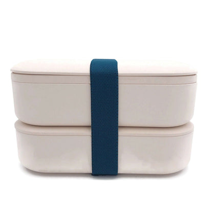 Beige two-tier lunch box stacked closed with a dark blue securing band