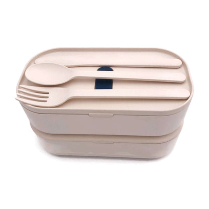 Fork, knife and spoon stored across the upper cover of the beige two-tier lunch box