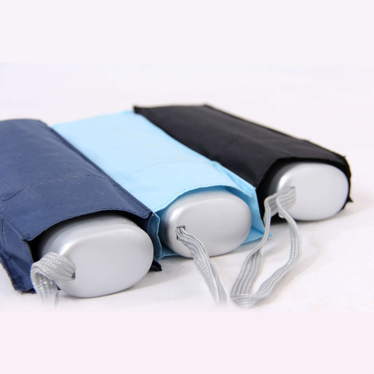 Close-up of navy, light blue and black folded mini umbrellas in sleeves with silver-colour handles and wrist loops