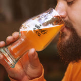Man enjoying a drink from a engraved Jack's & Co. beer glass in a cozy setting.