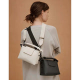 Woman wearing Gaston Luga Splashini Crossbody bags in white and black, showcasing adjustable straps.