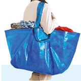 A woman carrying a blue Laundry Carrier Bag filled with clothes, showcasing its practicality and spacious design.